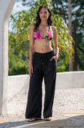 Woman wearing a colorful floral bikini top and black pants standing outdoors.