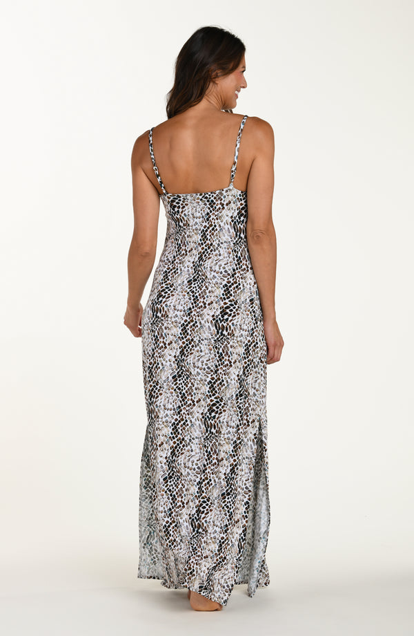 Full body back image of model wearing a sleeveless maxi cover-up dress with thin over the shoulder straps, pockets, and an allover taupe colored animal print.