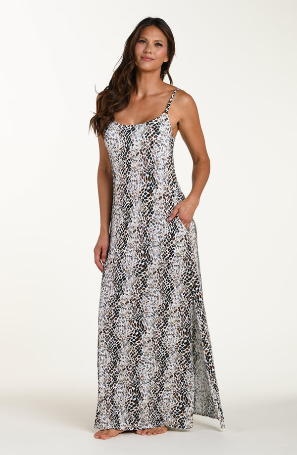 Full body front image of model wearing a sleeveless maxi cover-up dress with thin over the shoulder straps, pockets, and an allover taupe colored animal print.