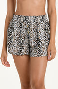 Front image of model wearing lightweight beach shorts with a black, white, and brown animal print pattern and an elastic drawstring waistband.