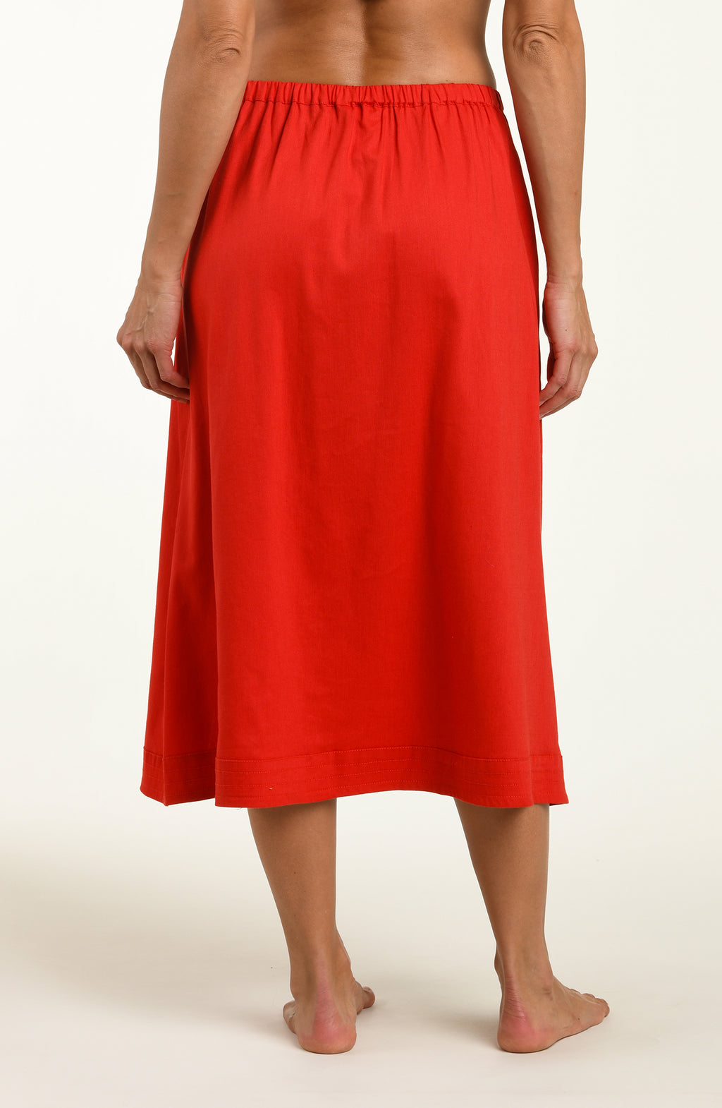 Woman wearing a red cover up skirt against a white background.