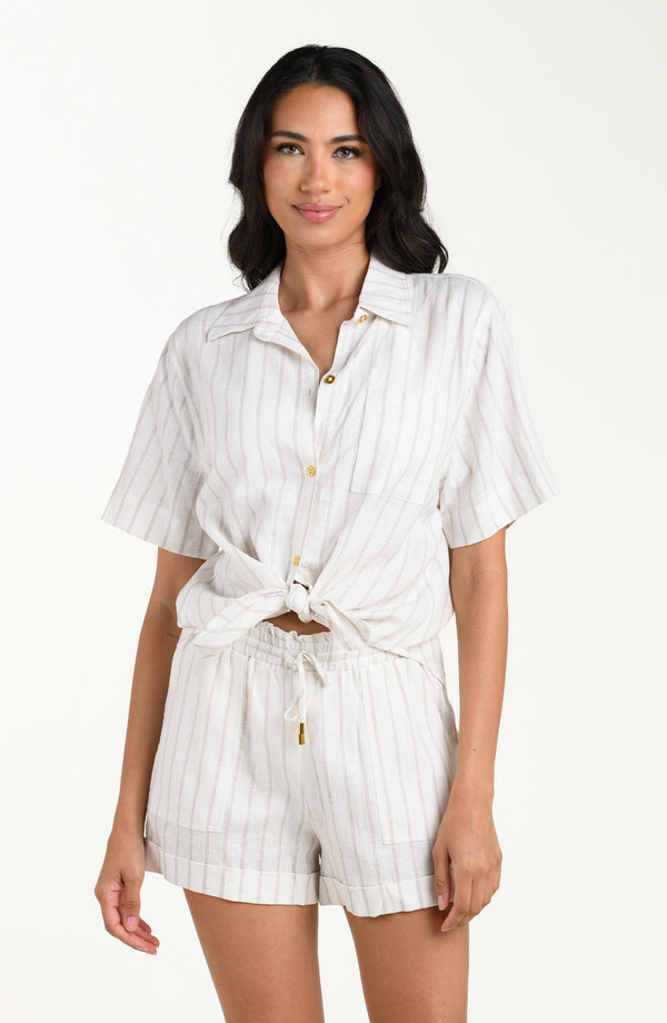 Front image of model wearing a cream striped colored short-sleeve cover-up shirt with button front, chest pocket, and tie-front waist. It's paired with matching beach shorts.