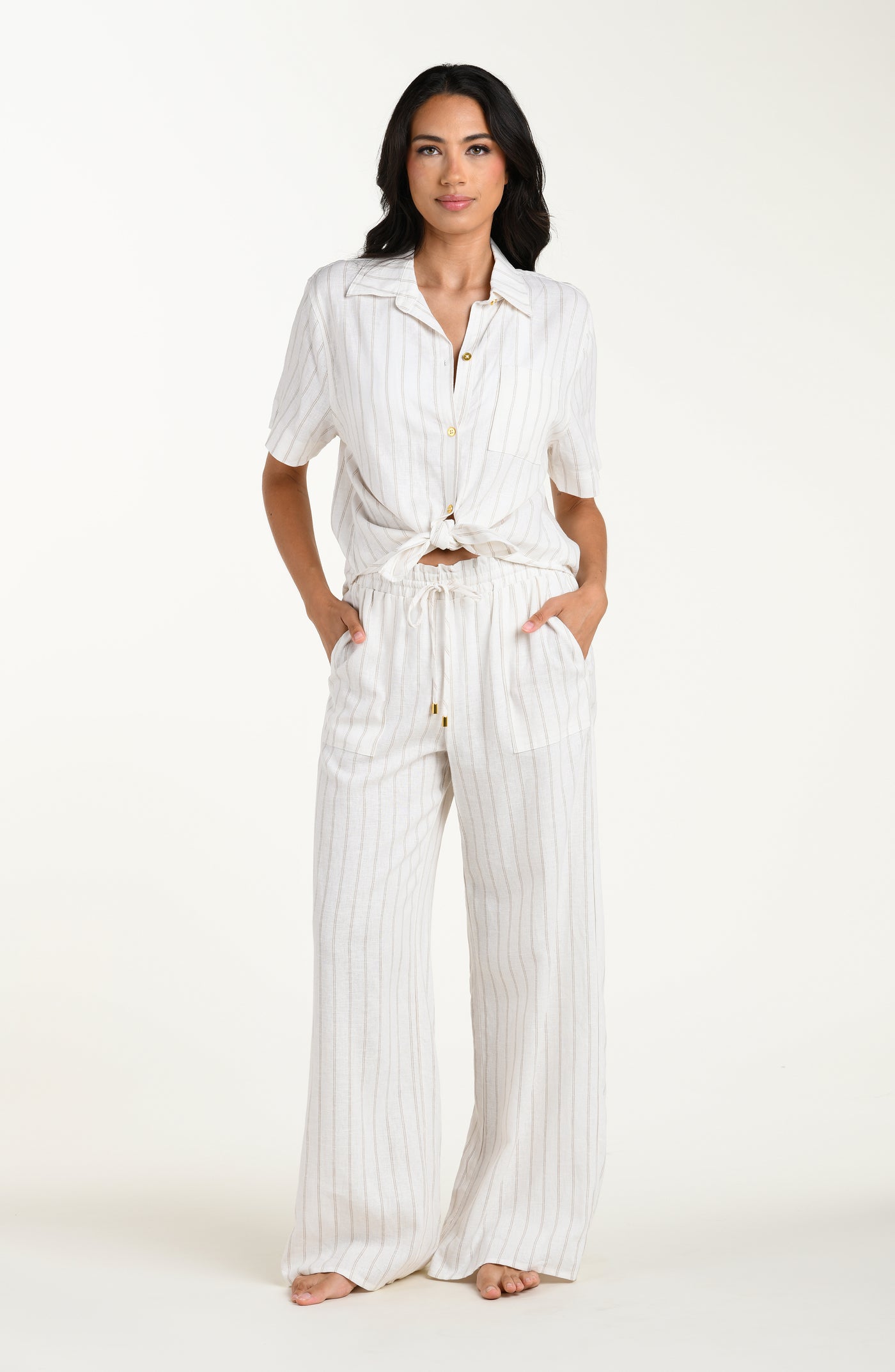 
                  
                    Front image of model wearing a cream striped colored short-sleeve cover-up shirt with button front, chest pocket, and tie-front waist.
                  
                