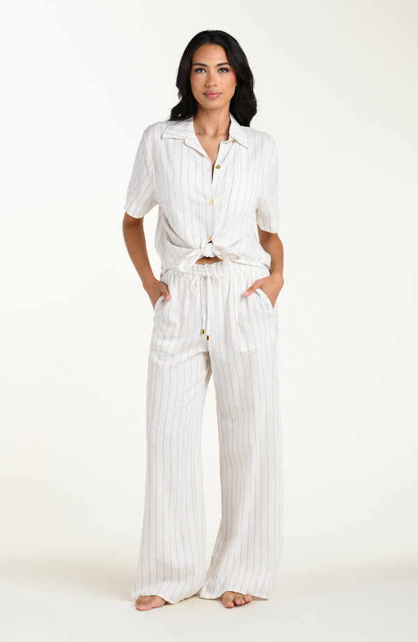 Front image of model wearing a cream striped colored short-sleeve cover-up shirt with button front, chest pocket, and tie-front waist.
