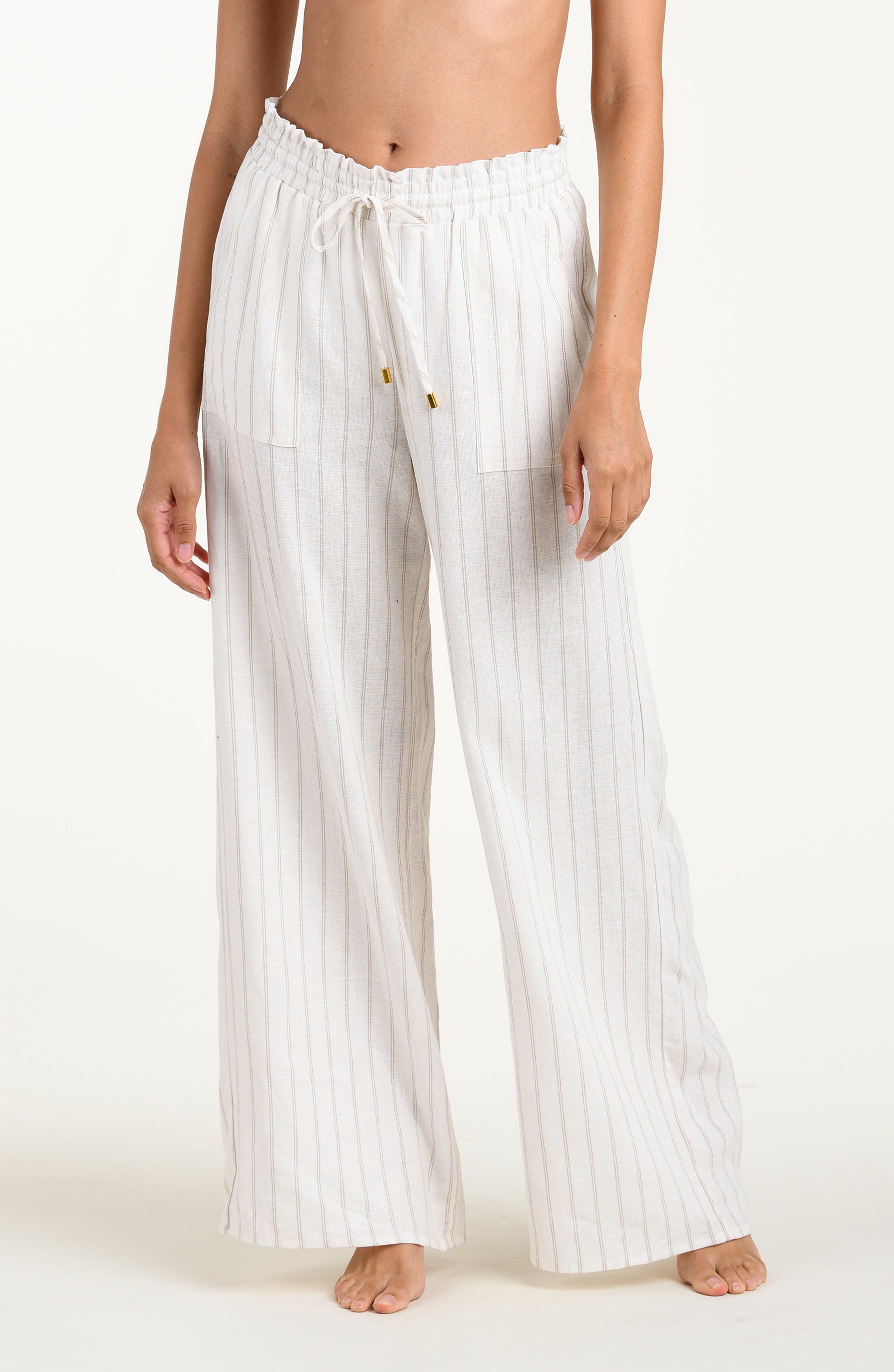 Front image of model wearing a cream striped colored wide-leg beach pants with a relaxed fit, drawstring waistband, and pockets.