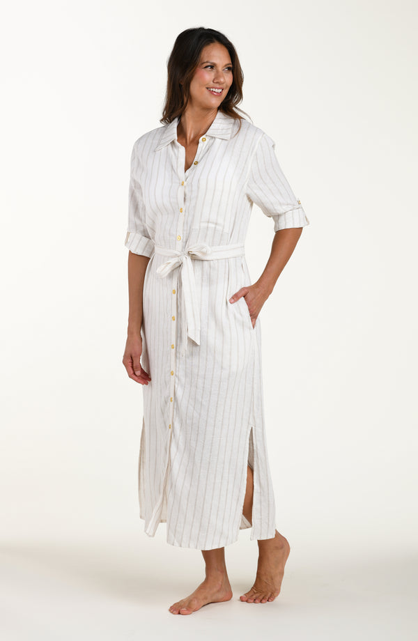 Full body front image of model wearing a cream striped colored button-down, shirt dress cover-up with roll-tab sleeves, a belted waist, and side slits. 