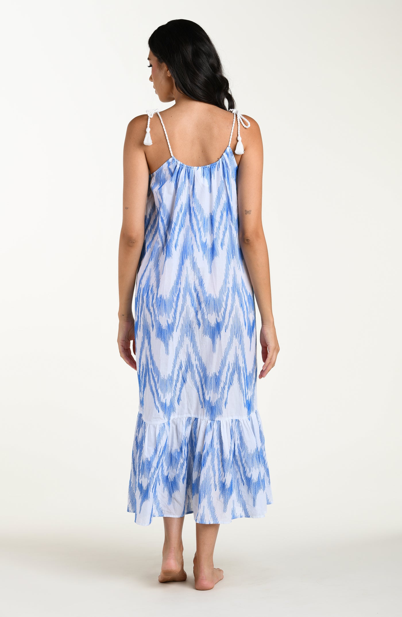 
                  
                    Full body back image of model wearing a light blue and white cover up dress featuring a maxi fit, loose flowy silhouette with adjustable shoulder ties for a customizable fit. 
                  
                