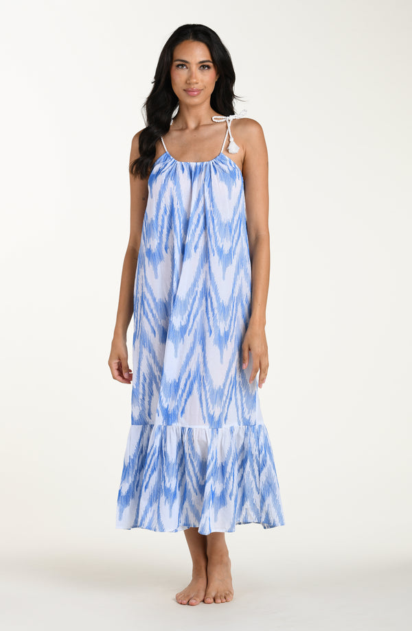 Full body front image of model wearing a light blue and white cover up dress featuring a maxi fit, loose flowy silhouette with adjustable shoulder ties for a customizable fit. 