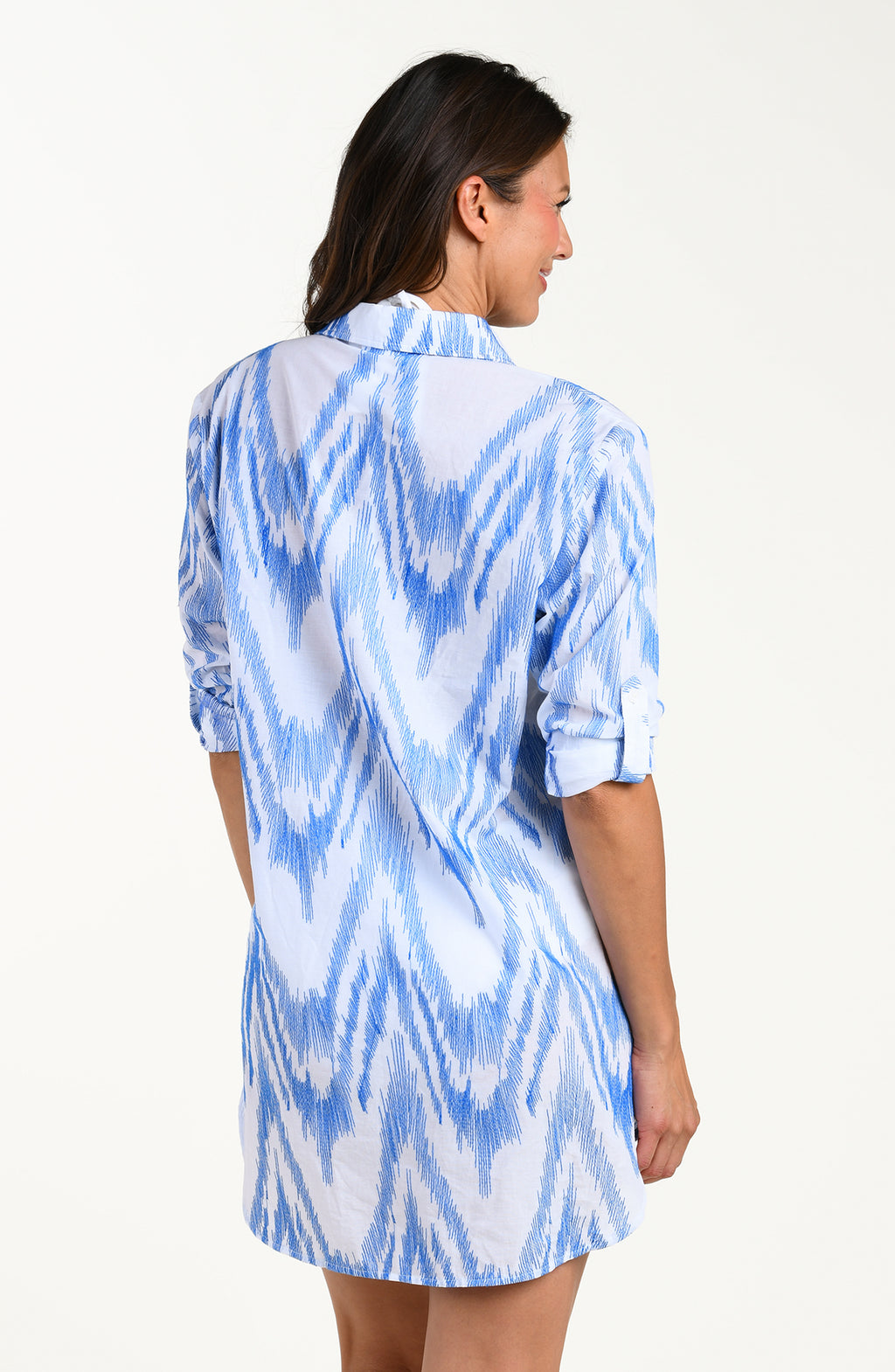 Back image of model wearing a light blue and white tunic cover-up featuring a relaxed, breezy fit with a button front, long sleeves and lightweight fabric that drapes. 