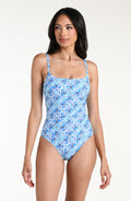 Woman wearing a blue patterned one piece swimsuit against a white background