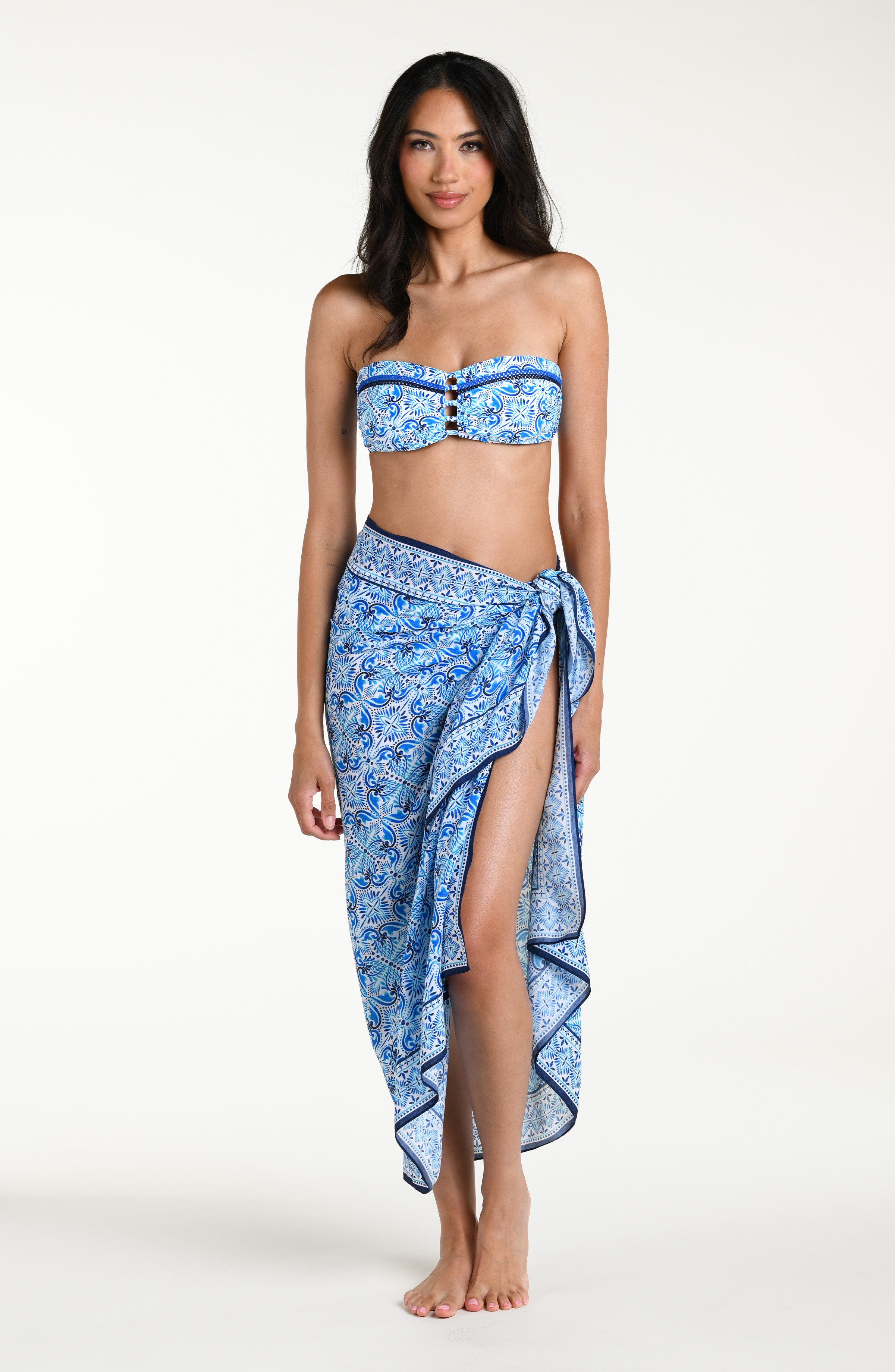 Woman wearing a blue floral patterned bikini top and matching sarong against a white background