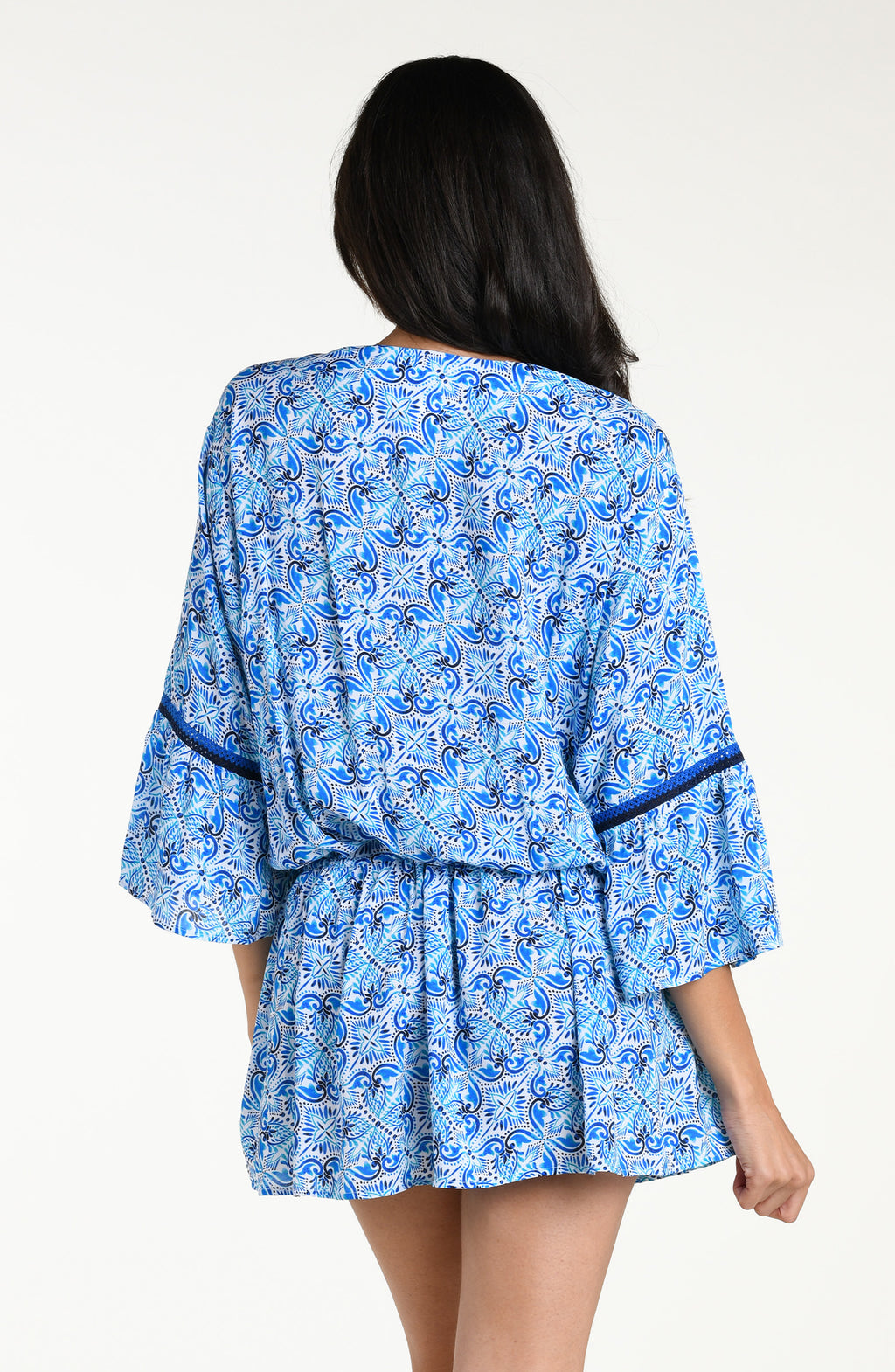 Woman wearing a blue floral patterned  V-neck tunic cover up against a white background