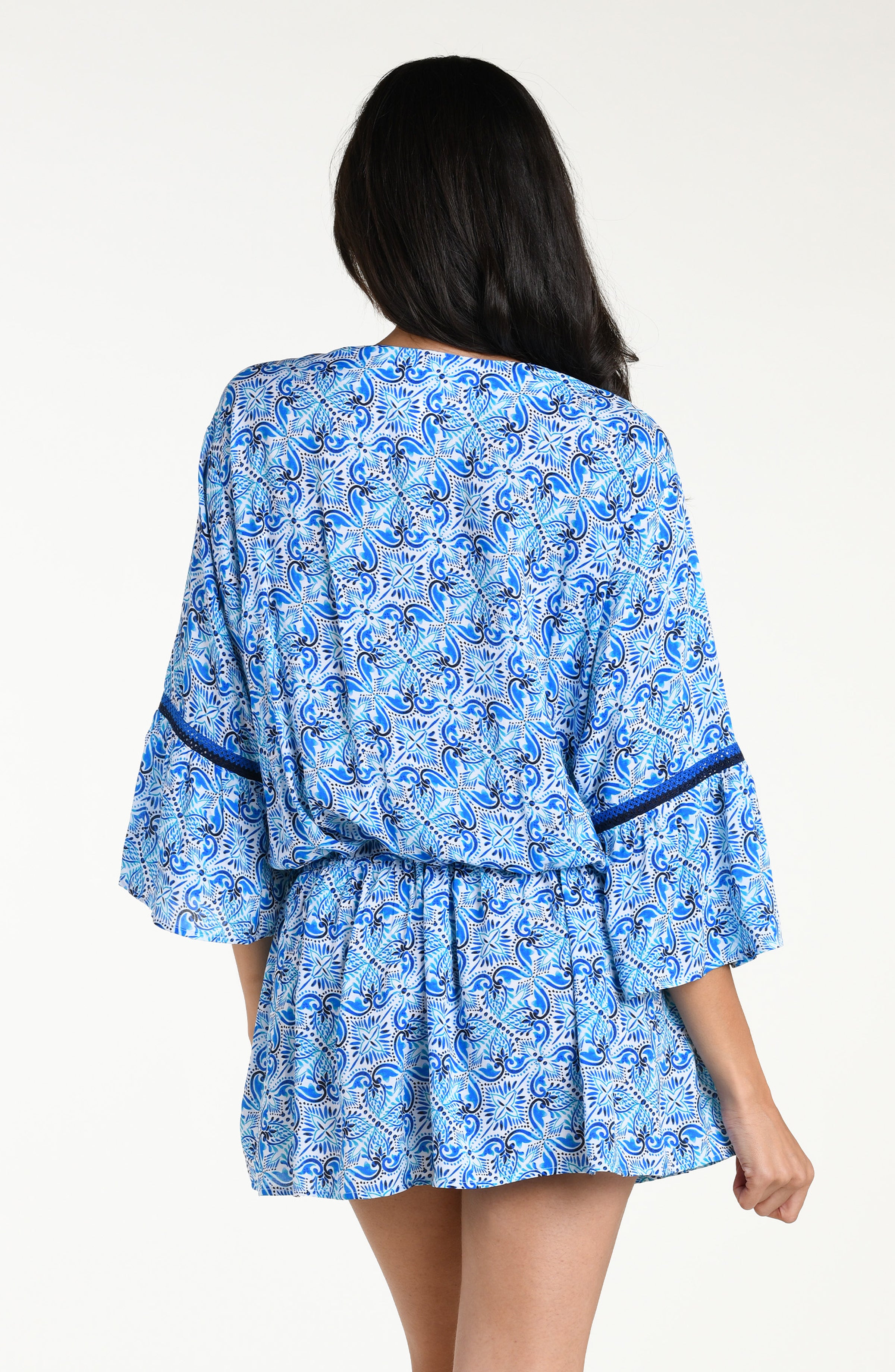 Woman wearing a blue floral patterned  V-neck tunic cover up against a white background