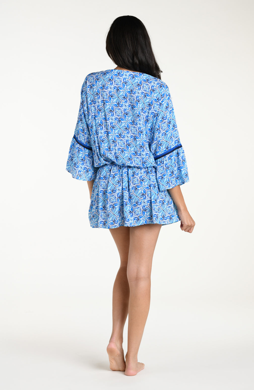 Woman wearing a blue floral patterned  V-neck tunic cover up against a white background