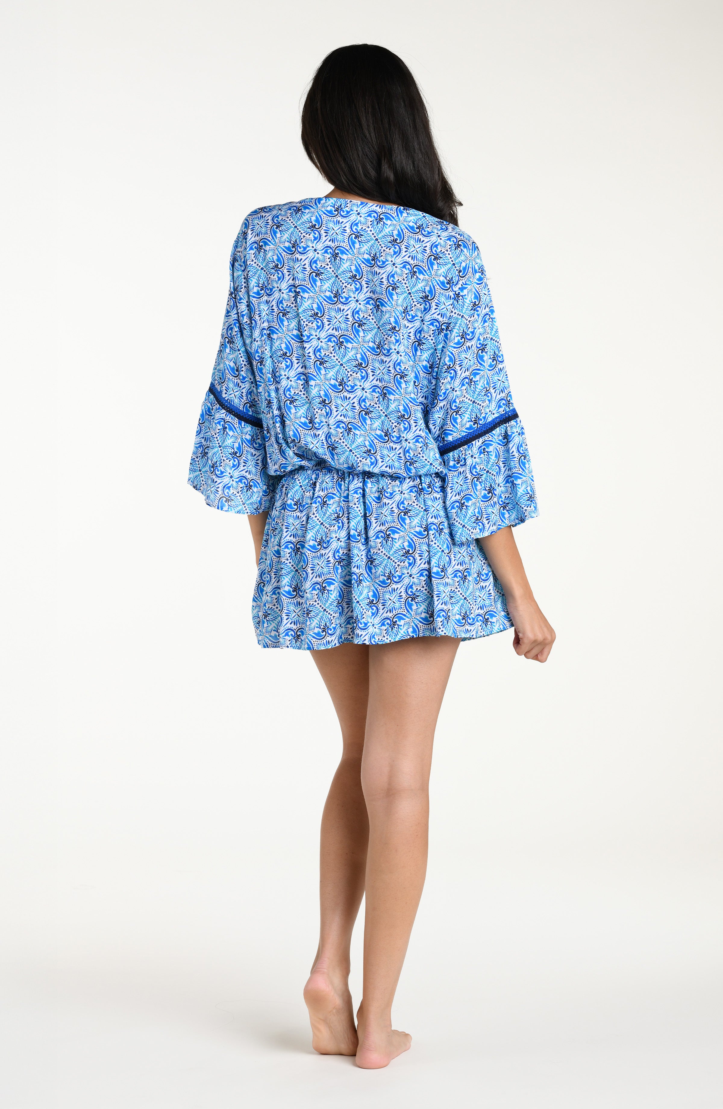 Woman wearing a blue floral patterned  V-neck tunic cover up against a white background