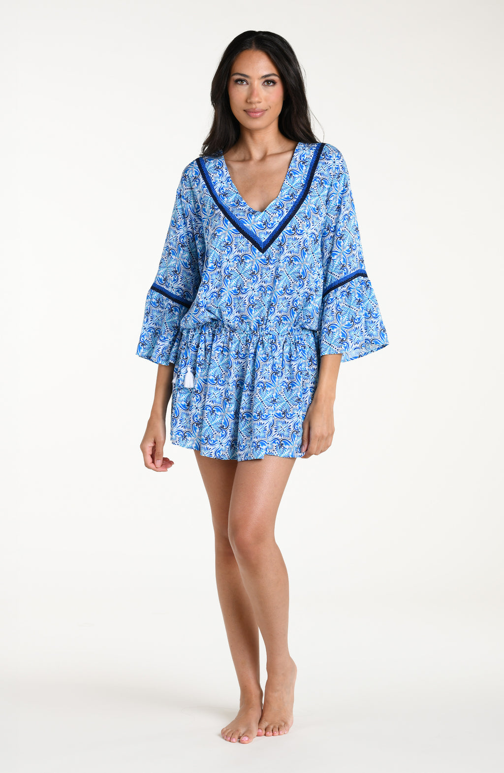 Woman wearing a blue floral patterned  V-neck tunic cover up against a white background