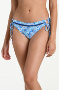 Woman wearing a blue patterned bikini bottom against a white background.