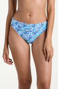 Woman wearing a blue patterned bikini bottom against a white background.