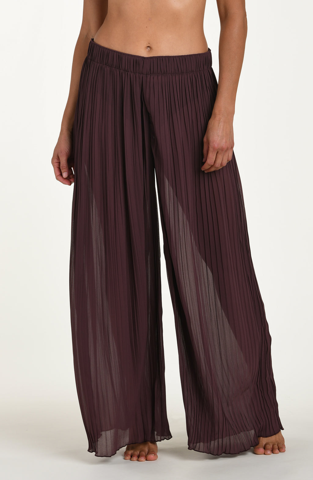 Brown pleated pants worn by a person on a white background