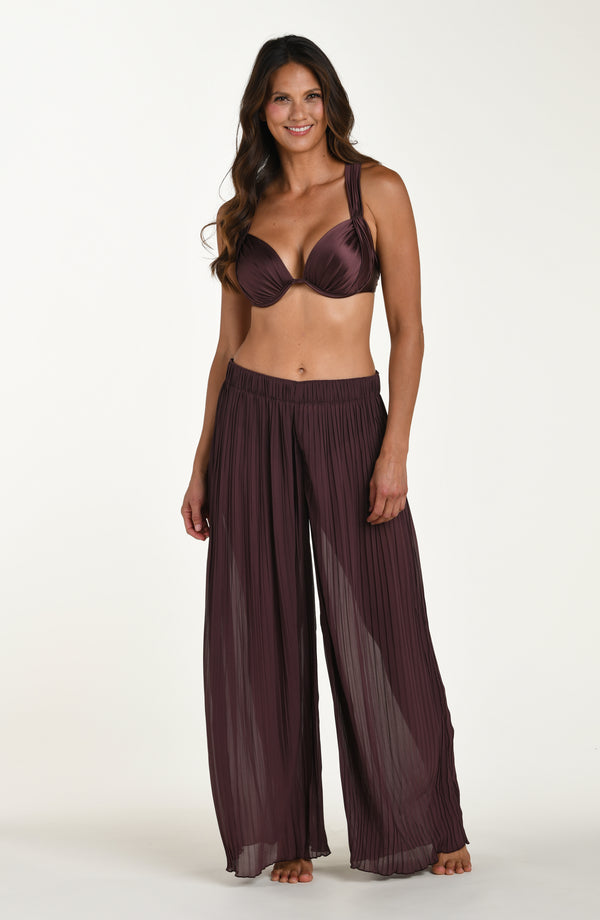Woman wearing a dark purple bra and wide-leg pants on a white background