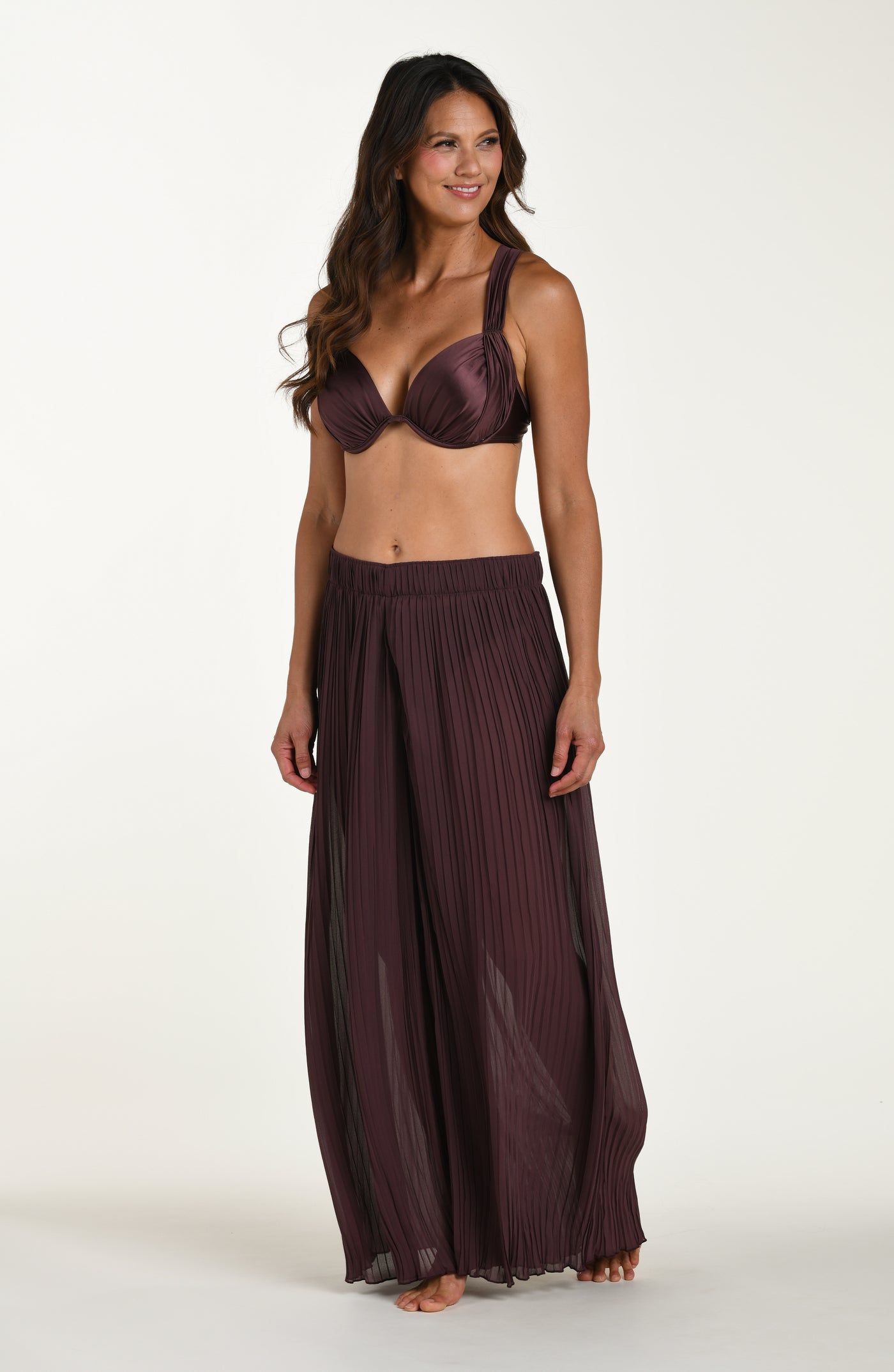 
                  
                    Woman wearing a dark purple bikini set with a matching skirt on a white background
                  
                