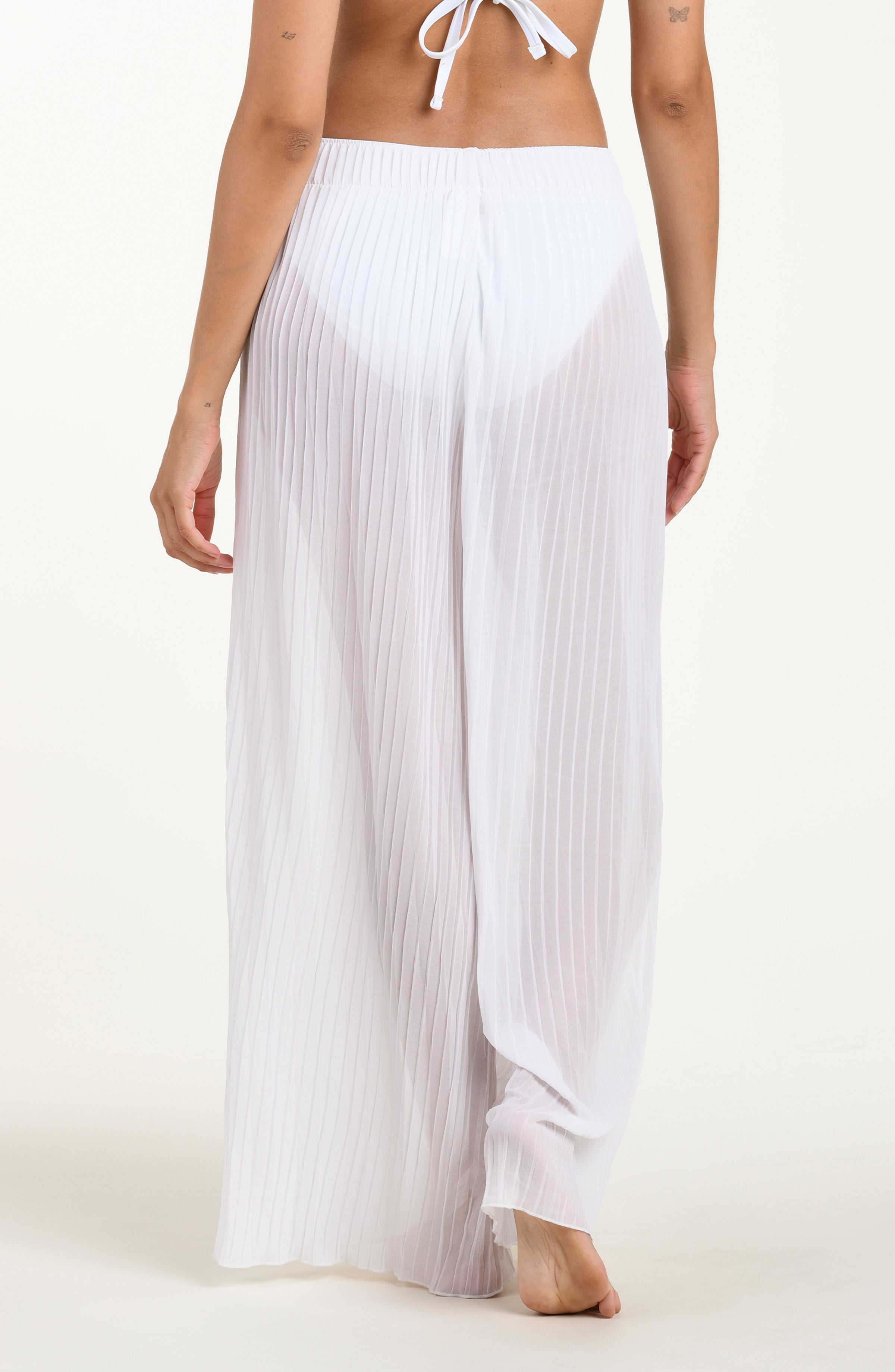 White pleated pants worn by a person on a white background