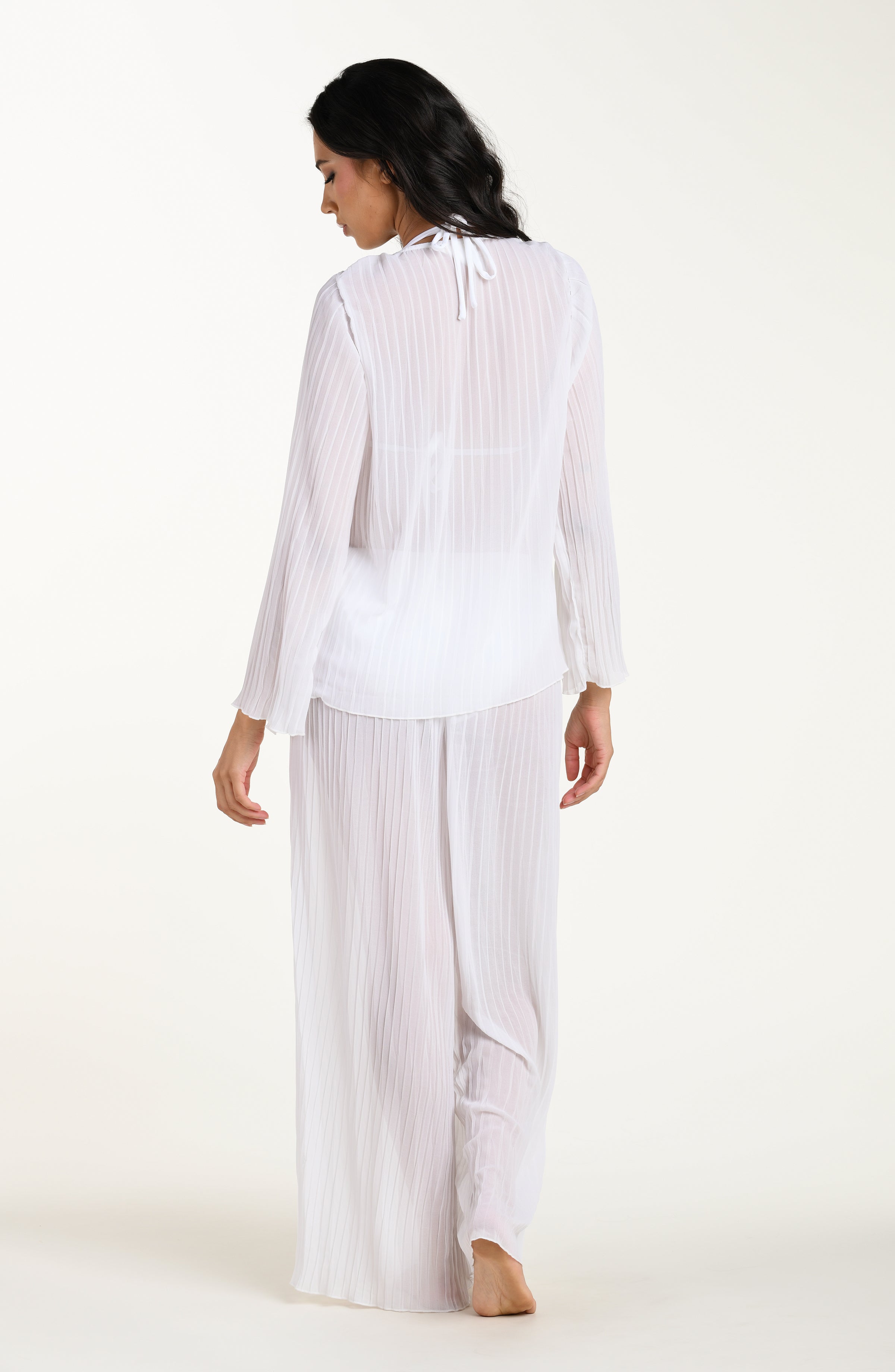 Woman wearing a white striped shirt and wide-leg pants on a white background