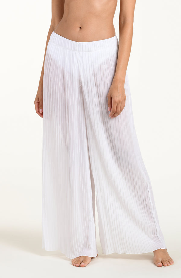 Person wearing white pleated pants on a plain background