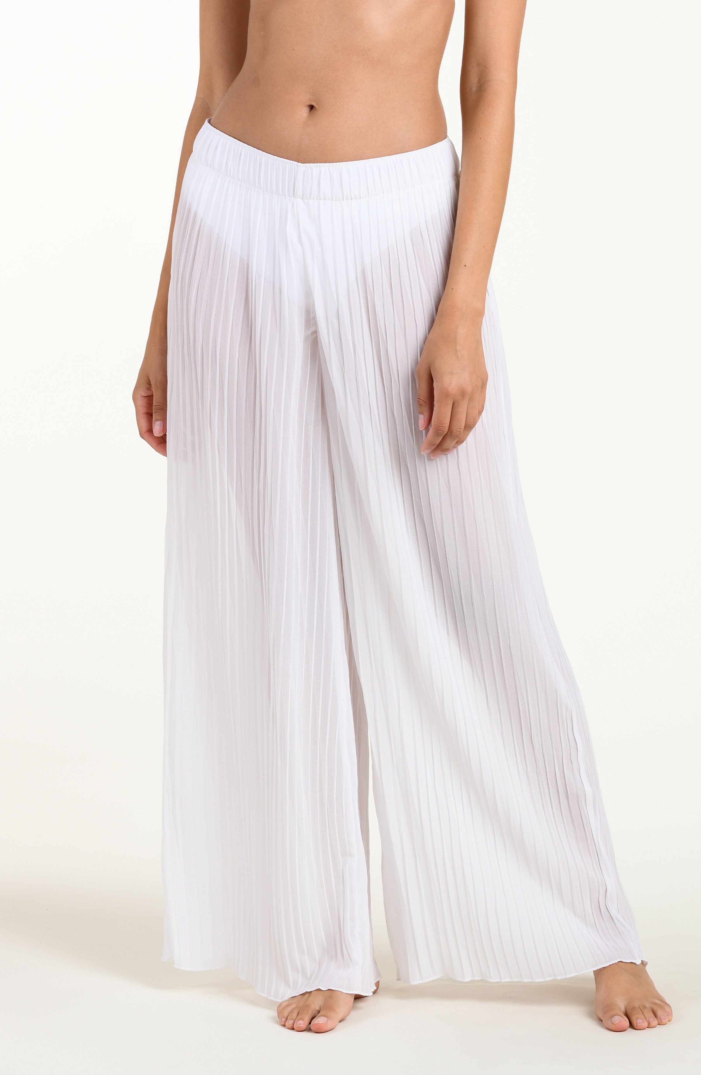 Person wearing white pleated pants on a plain background