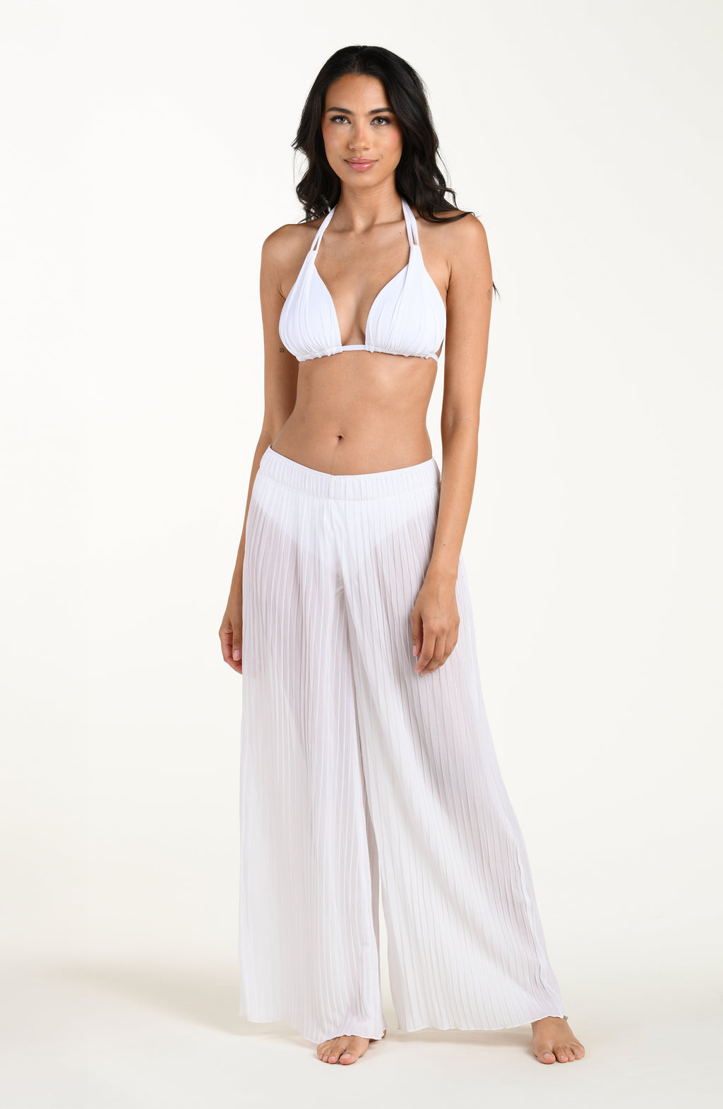 Woman wearing a white halter top and wide-leg pants on a white background