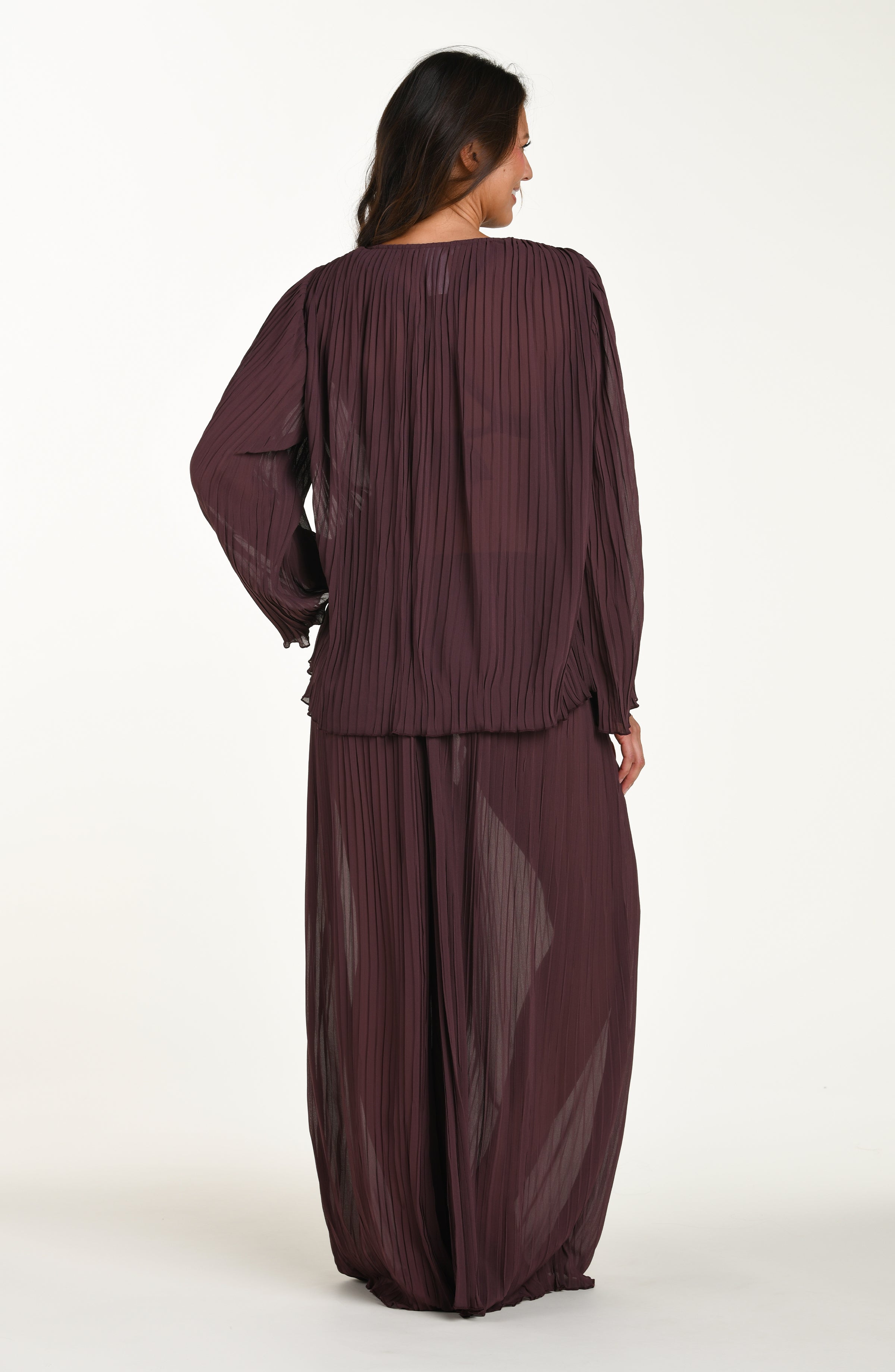 Woman wearing a long burgundy dress with sheer overlay on a white background