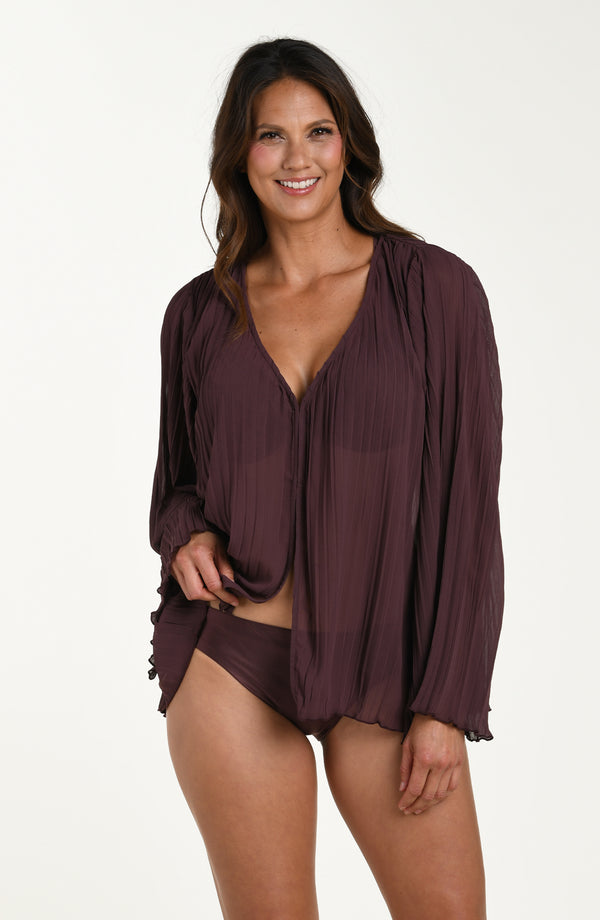 Woman wearing a dark purple cover-up over a swimsuit on a white background