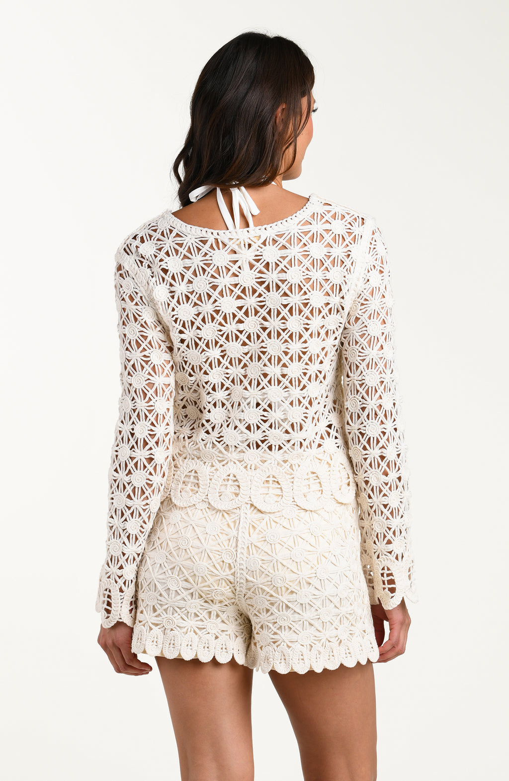 Woman wearing a white lace outfit on a plain background