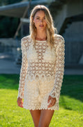 Woman wearing a white lace dress standing on grass with a blurred background