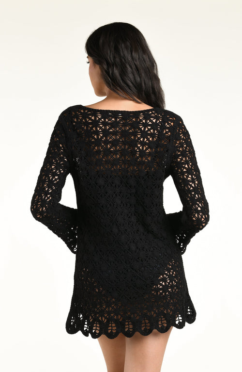 A woman modeling a black long-sleeve crochet kimono cover-up with a scalloped hem and front tie detail, photographed against a plain white studio background.