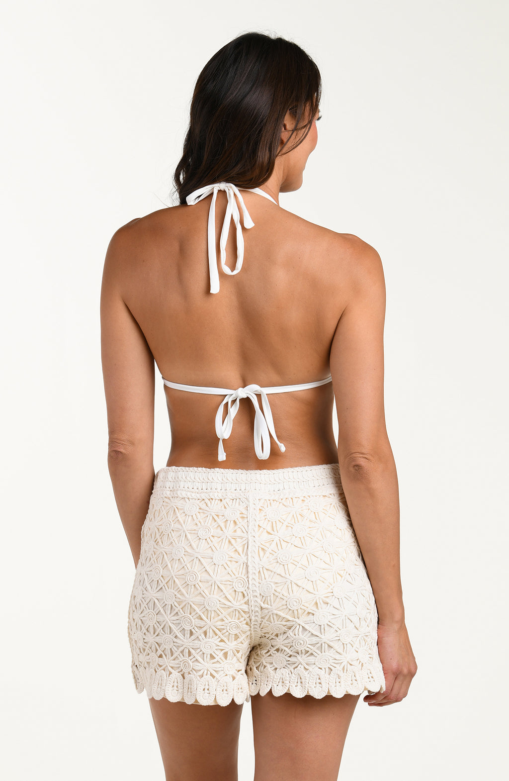 Woman wearing a white lace top and shorts set on a plain background