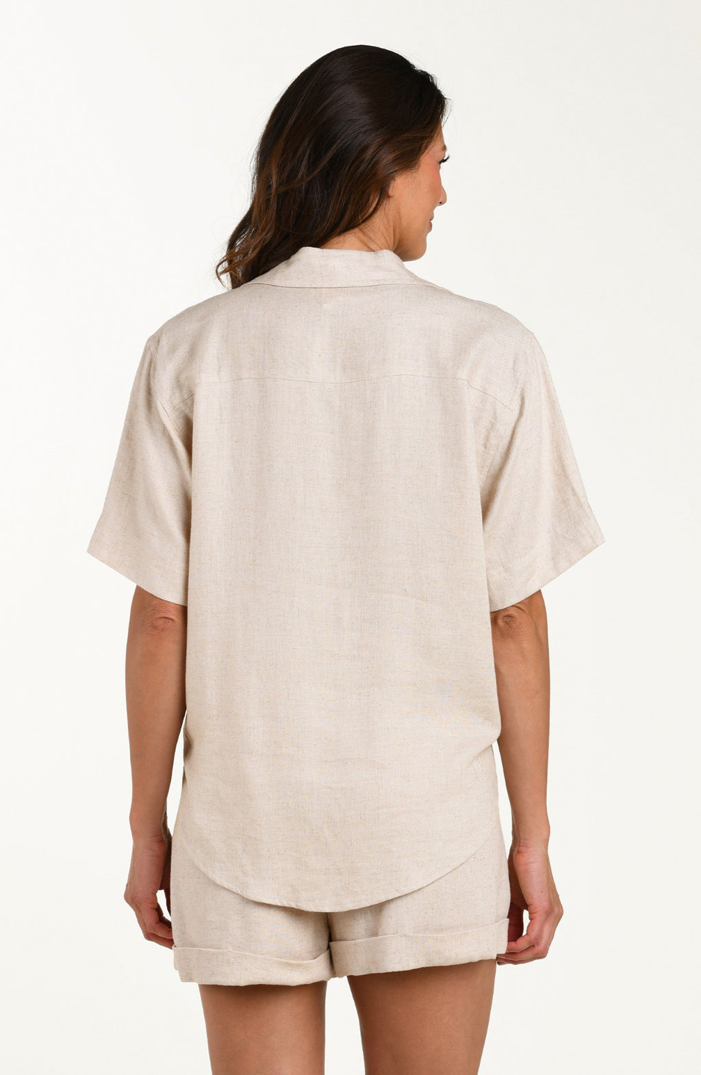 Back image of model wearing a taupe colored short-sleeve cover-up shirt with button front, chest pocket, and tie-front waist. It's paired with matching beach shorts.