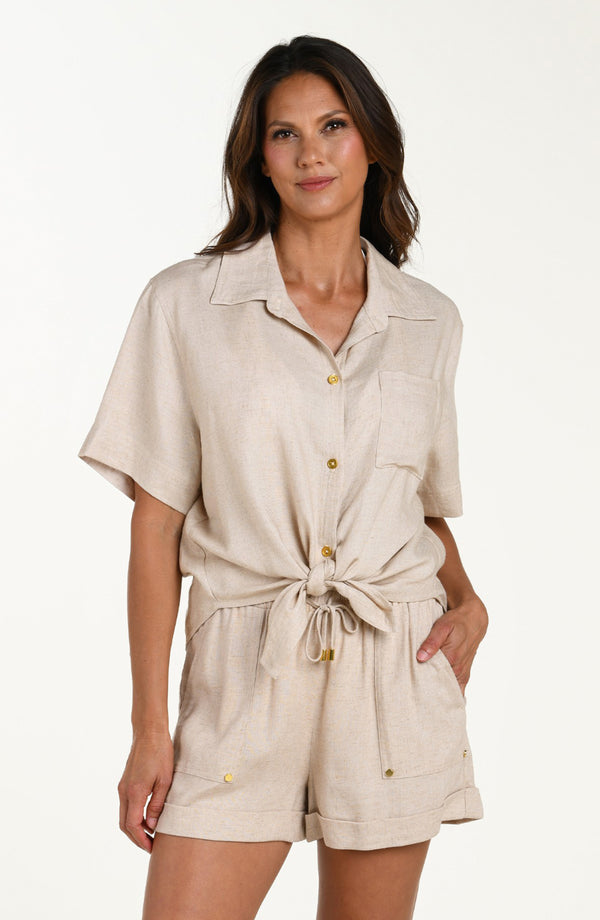 Front image of model wearing a taupe colored short-sleeve cover-up shirt with button front, chest pocket, and tie-front waist. It's paired with matching beach shorts.