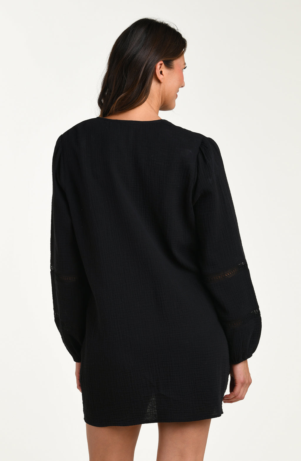 Back image of model wearing a black long-sleeve tunic cover-up with sheer lace trim accents on the sleeves.
