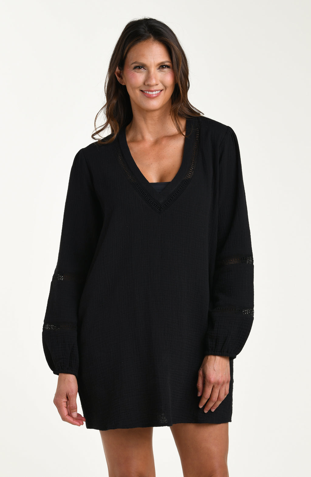 Front image of model wearing a black long-sleeve tunic cover-up with a V-neckline and sheer lace trim accents. 