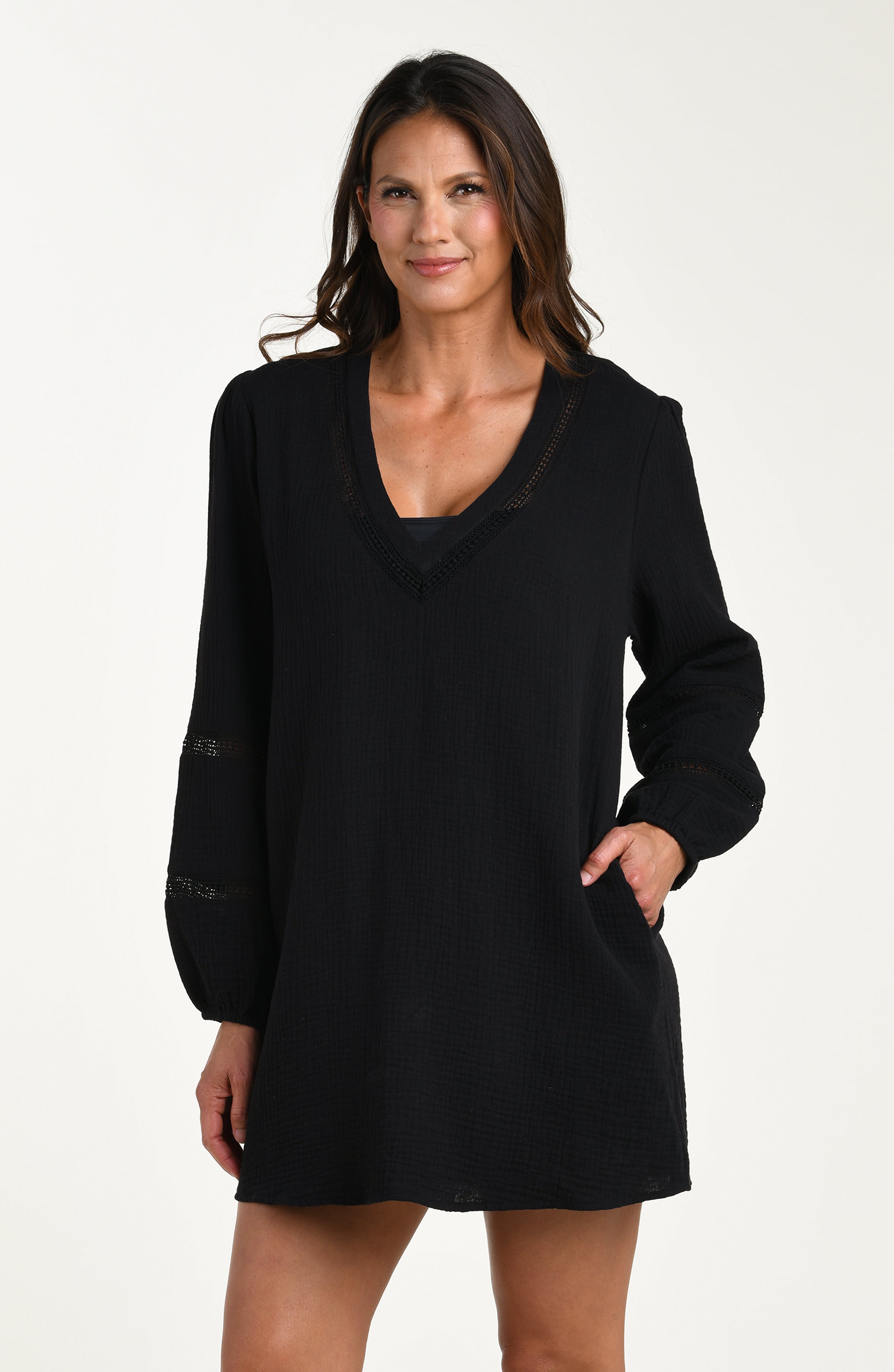 Front image of model wearing a black long-sleeve tunic cover-up with a V-neckline and sheer lace trim accents. 