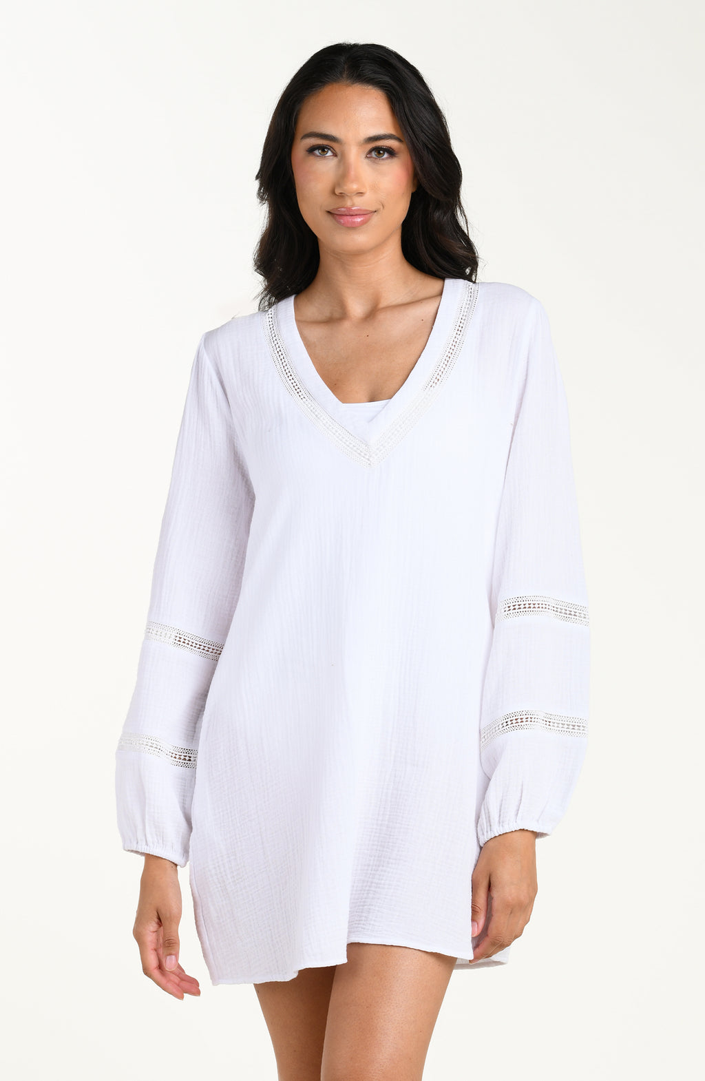 Front image of model wearing a white long-sleeve tunic cover-up with a V-neckline and sheer lace trim accents. 