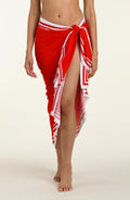 Woman wearing a red and white patterned sarong on a plain background