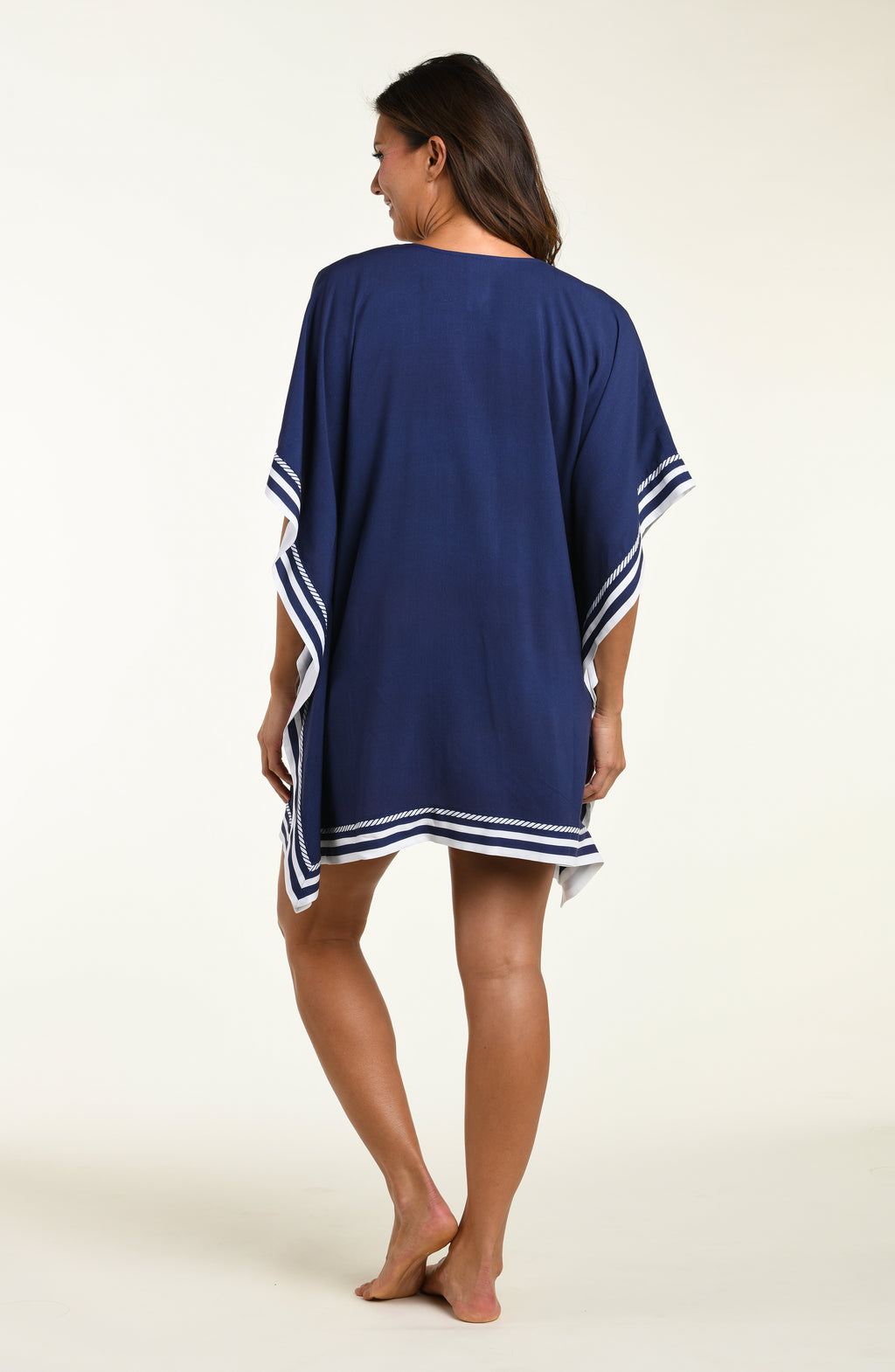 Woman wearing a navy blue tunic cover up with white floral patterns on a white background