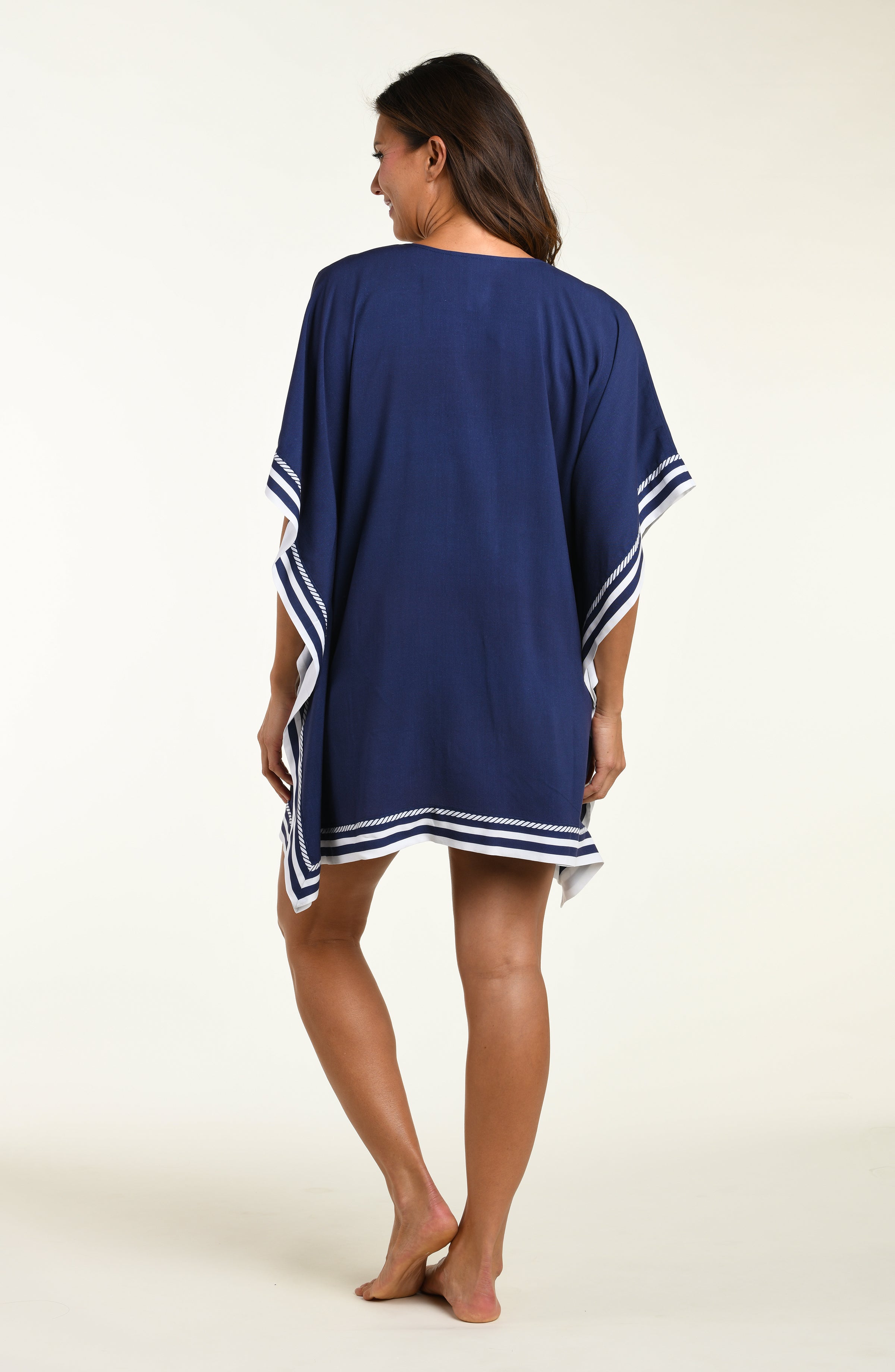 Woman wearing a navy blue tunic cover up with white floral patterns on a white background