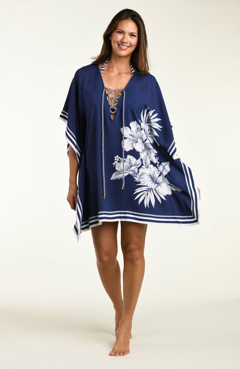 Woman wearing a navy blue tunic cover up with white floral patterns on a white background