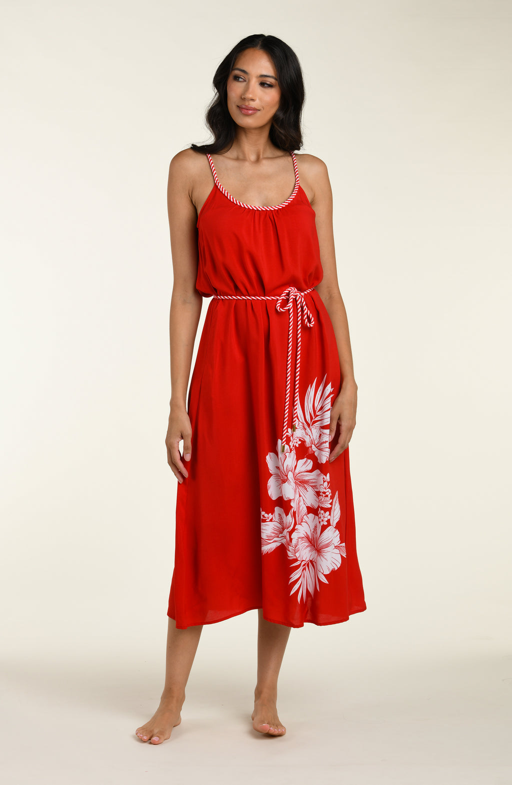 Woman wearing a red cover up dress with white floral patterns on a plain background
