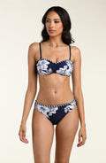 Woman wearing a navy blue and white floral bikini top and matching bottom against a beige background