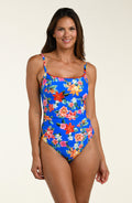 Woman wearing a blue floral one-piece swimsuit on a beige background