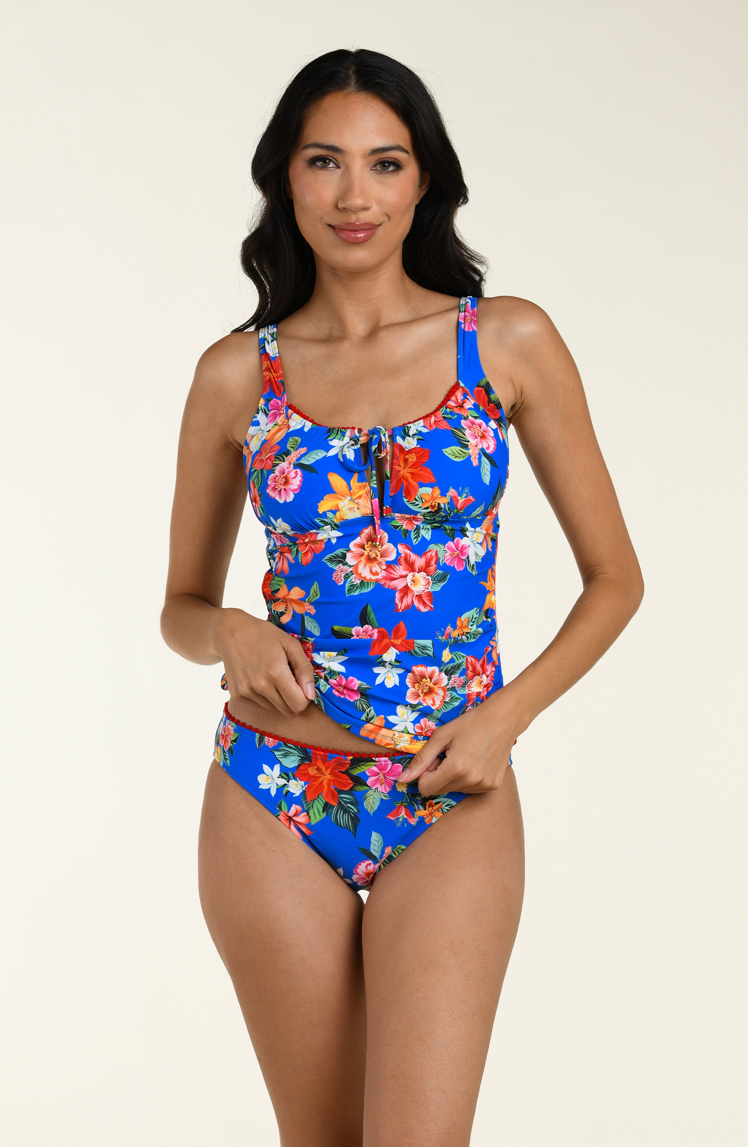 Woman wearing a colorful floral tankini top and matching bottom on a beige background